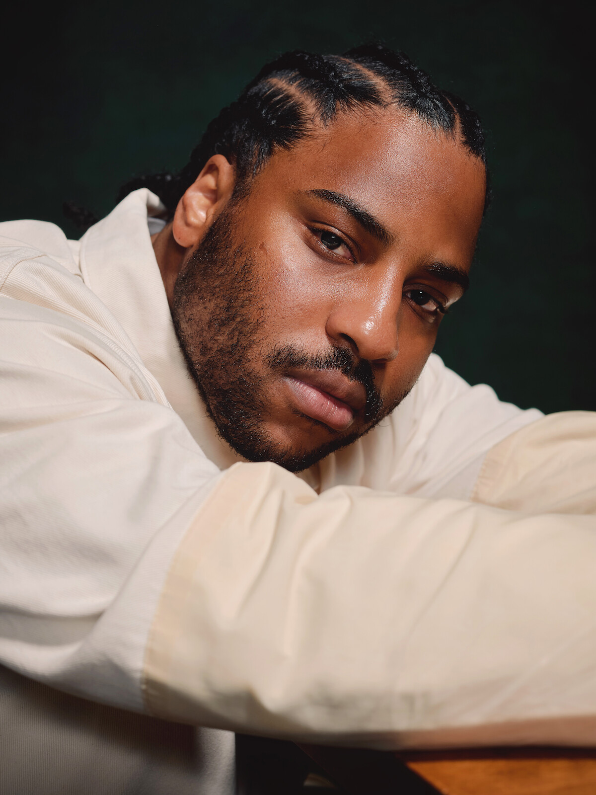 Malcolm Washington wears a white jacket against a dark gray background.
