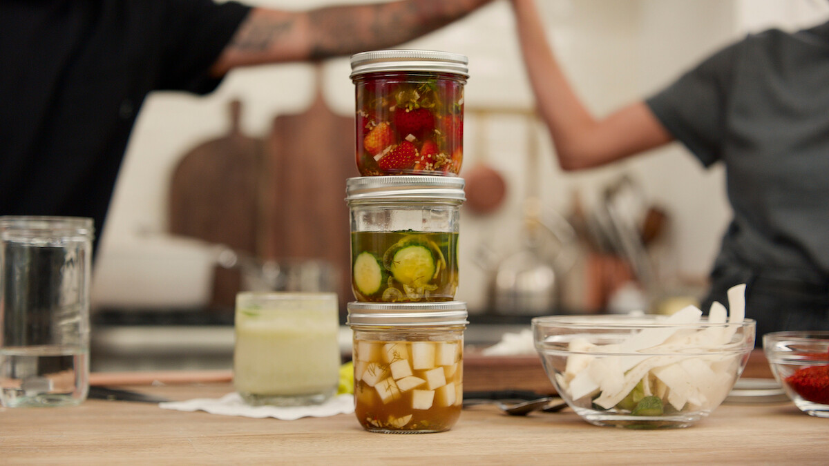 Three jars of pickled fruits and vegetables stacked on top of each other.