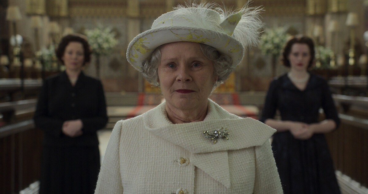 The Queen dressed in a pantsuit featuring a fancy hat and a sparkly broach