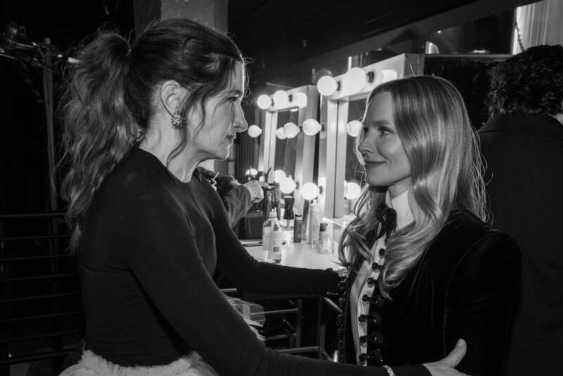 Kathryn Hahn and Kristen Bell lock eyes with each other in profile.