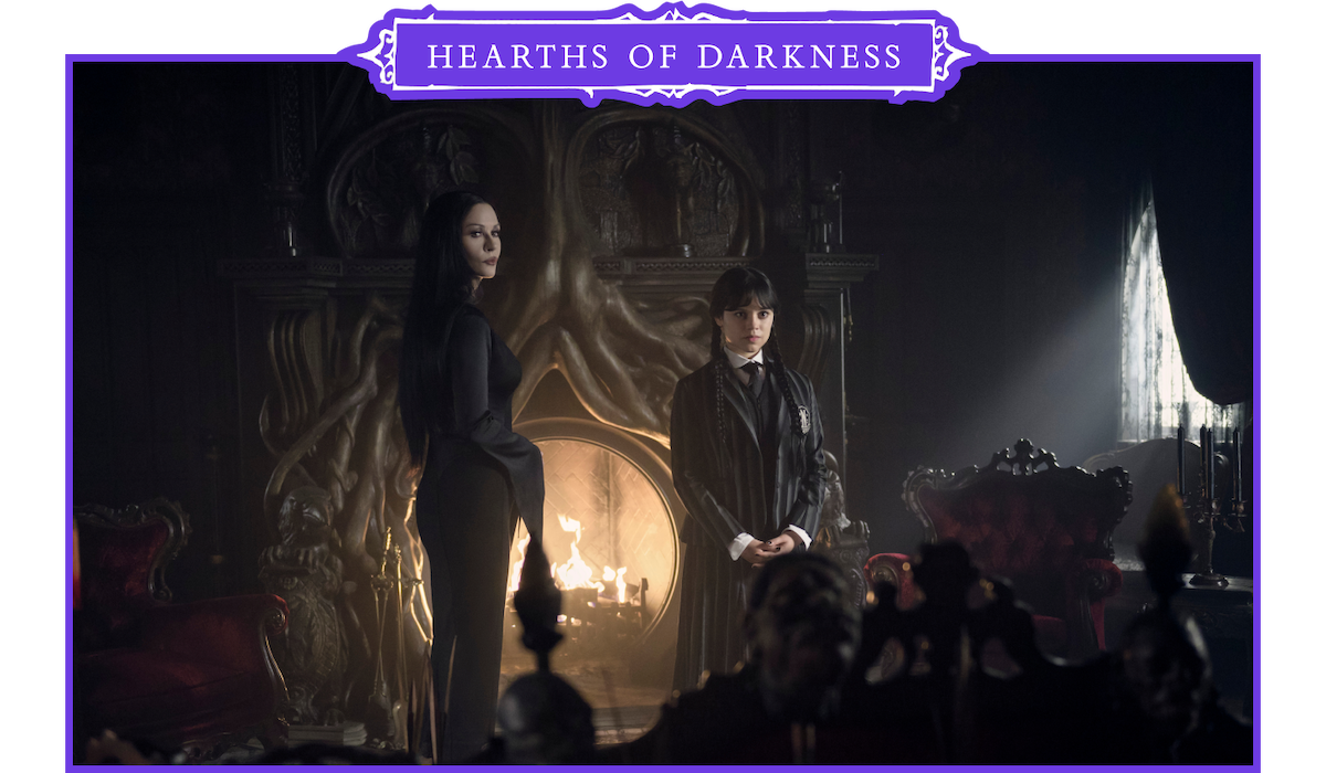 Catherine Zeta-Jones as Morticia Addams and Jenna Ortega as Wednesday Addams stand in front of a fireplace in ‘Wednesday’ Season 2.