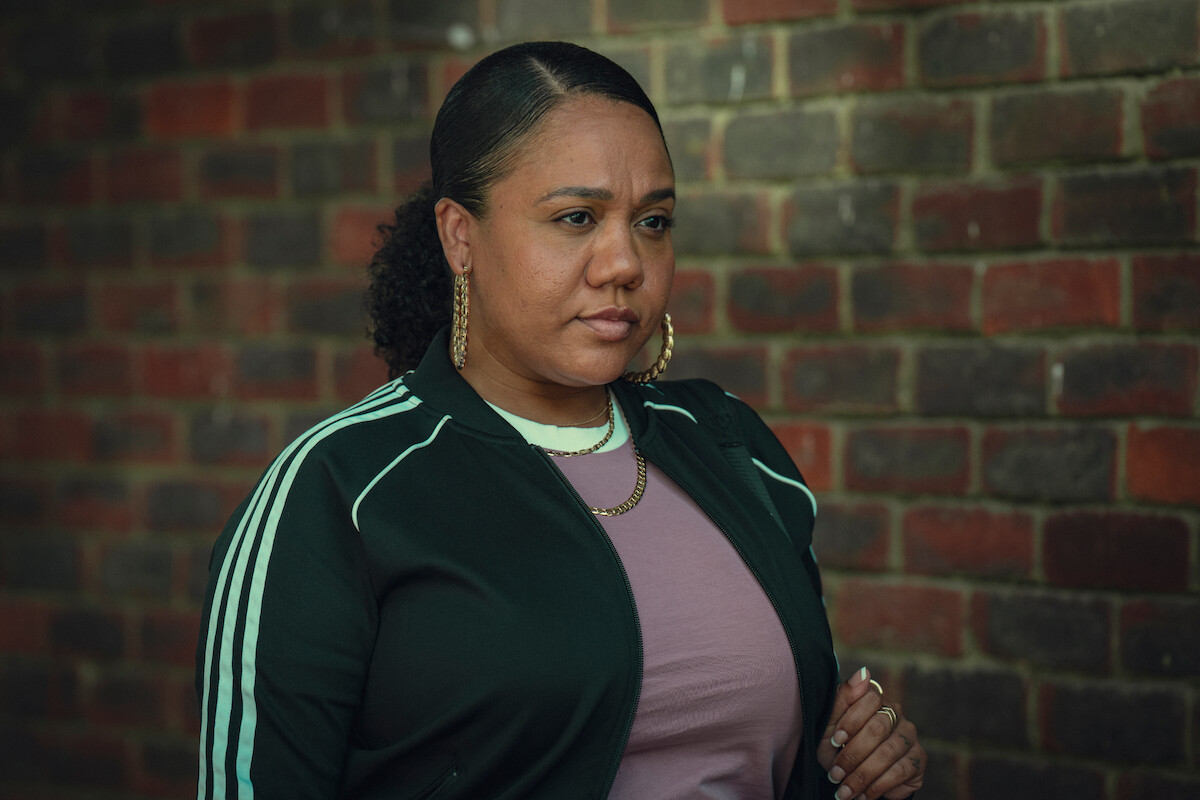 Natalie Athanasiou 'NoLay' as Mandy stands in front of a brick wall in Season 3 of ‘Top Boy.’