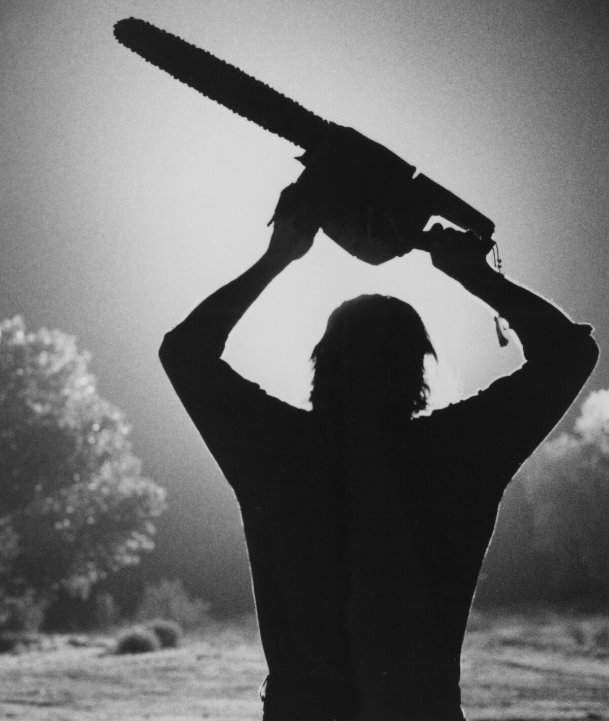 Leatherface raising a chainsaw above his head