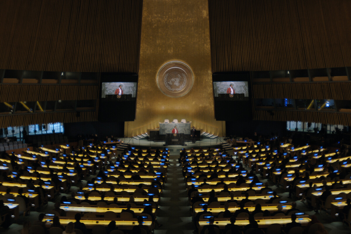 A conference room full of desks with a speaker at the podium