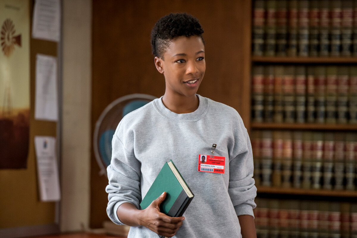 Samira Wiley as Poussey Washington holds a green book inside a library in Season 5 of ‘Orange Is the New Black.’