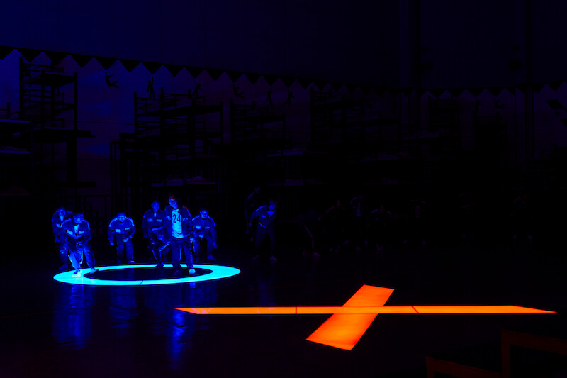 A glowing blue circle and red X on the floor of a large room in Season 2 of 'Squid Game'