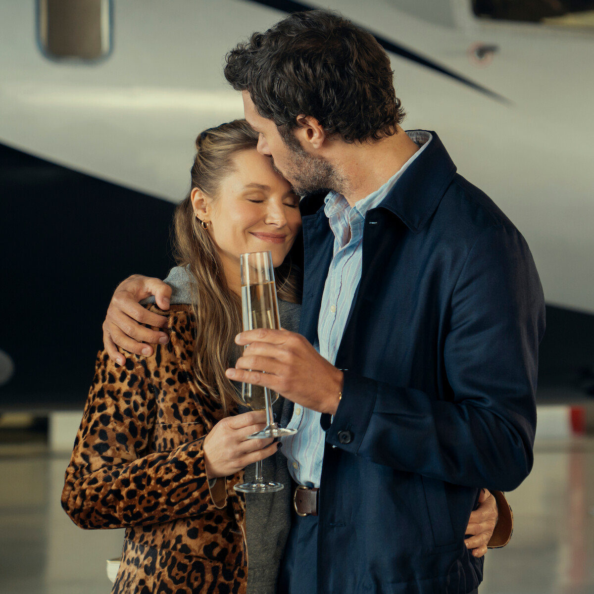 Um casal se abraça e enquanto bebe champanhe em um aeroporto