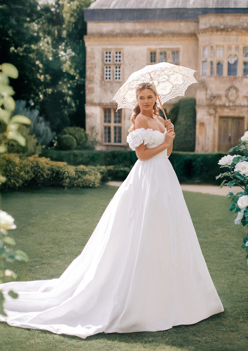 Woman in bridal dresses poses and looks off into the distance.