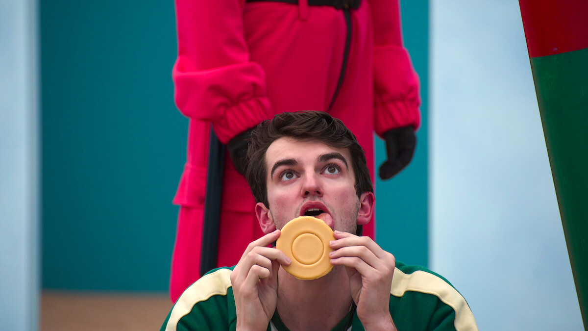 ‘Squid Game: The Challenge’ contestant licking his Dalgona cookie.