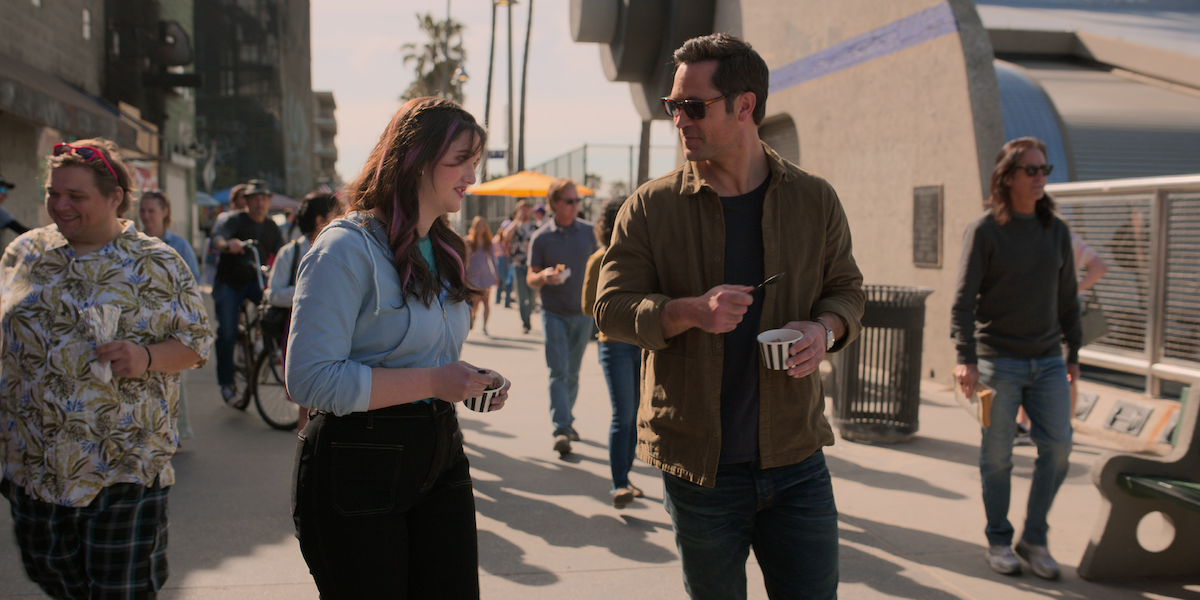 Krista Warner as Hayley Haller and Manuel Garcia-Rulfo as Mickey Haller walking on the Venice Beach Boardwalk
