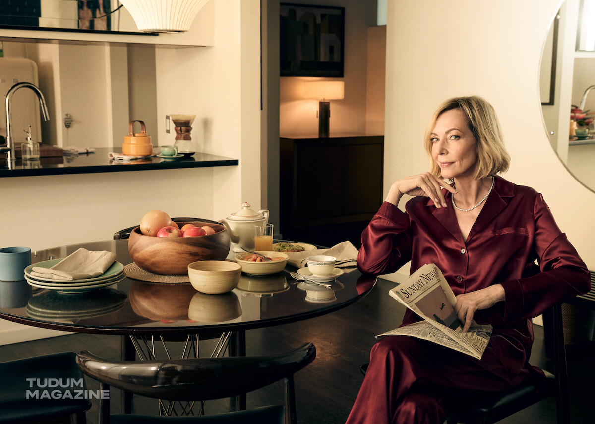 Allison Janey lendo um jornal na mesa da cozinha