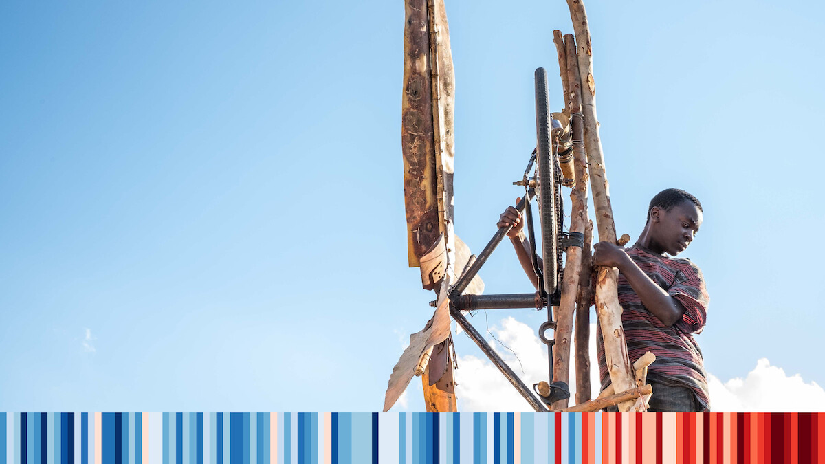 A young Malawian boy standing next to the windmill he built out of salvaged materials.