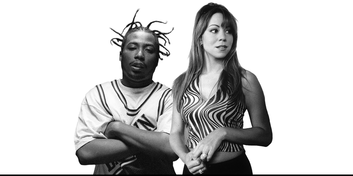 Two people standing together indoors, one with styled hair and streetwear outfit, the other with long hair in a patterned sleeveless top. Both look forward; monochrome image with casual atmosphere.