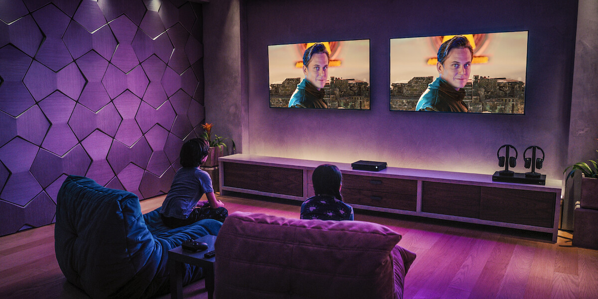 Connor Esterson as Tony Tang-Torrez and Everly Carganilla as Patty Tango-Torrez look on as Hyskor is displayed on the television in 'Spy Kids: Armageddon.'