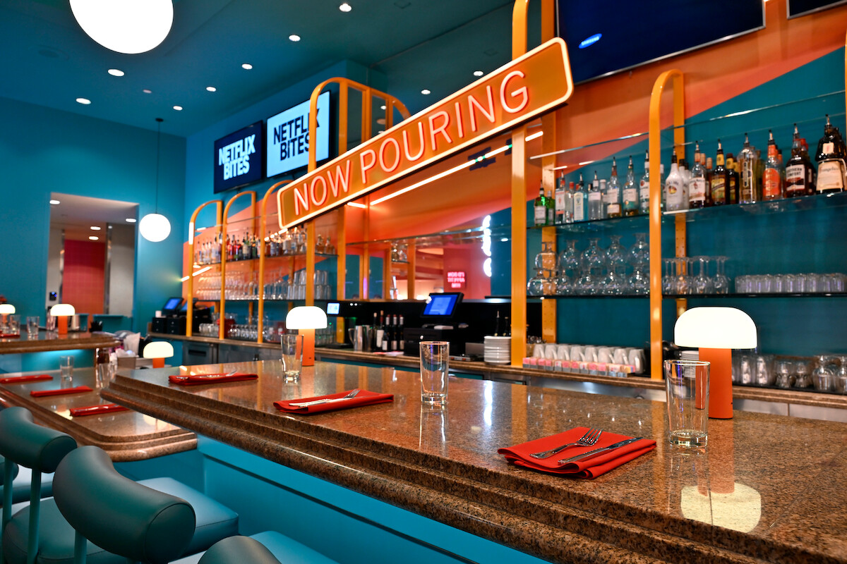 A view of the bar at NETFLIX BITES Vegas at the MGM Grand & Casino with a neon sign that reads “NOW POURING”