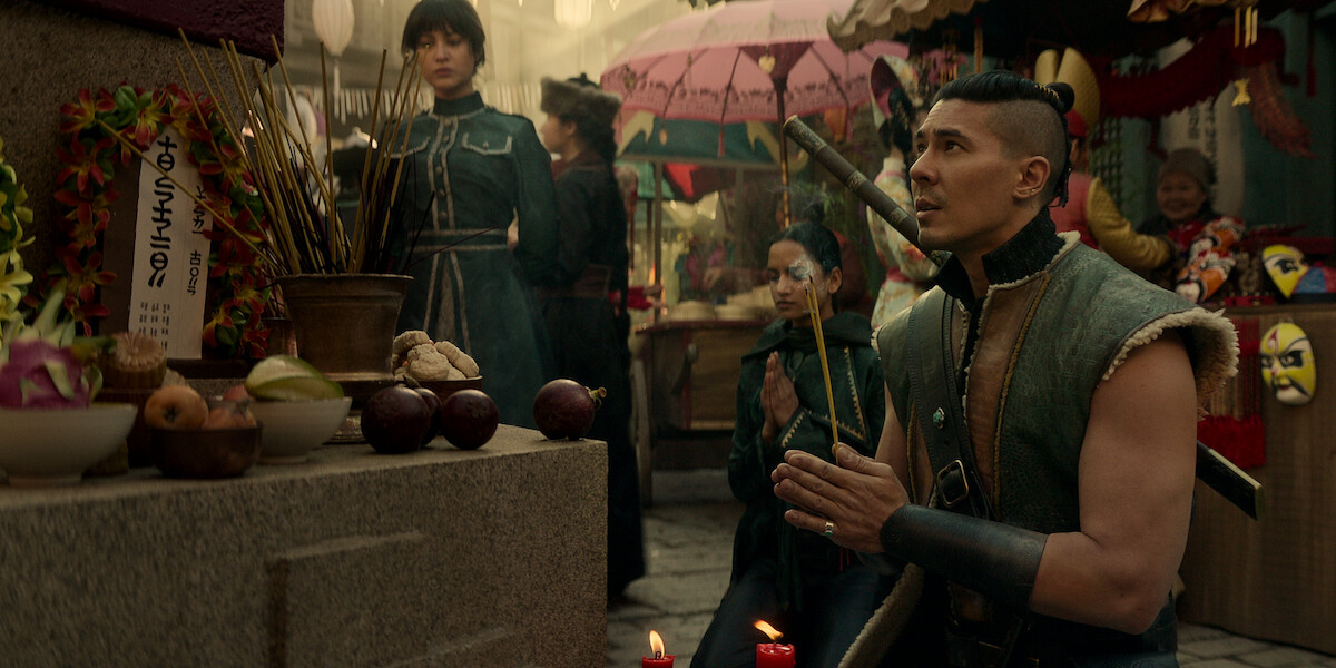 Lewis Tan prays in front of an altar as Tolya, accompanied by Zoya and Inej 