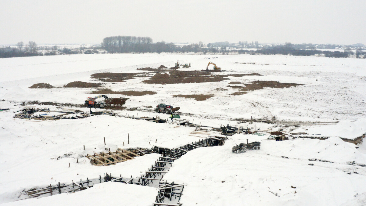 Trenches reinforced with wood planks dug into a snowy landscape. 