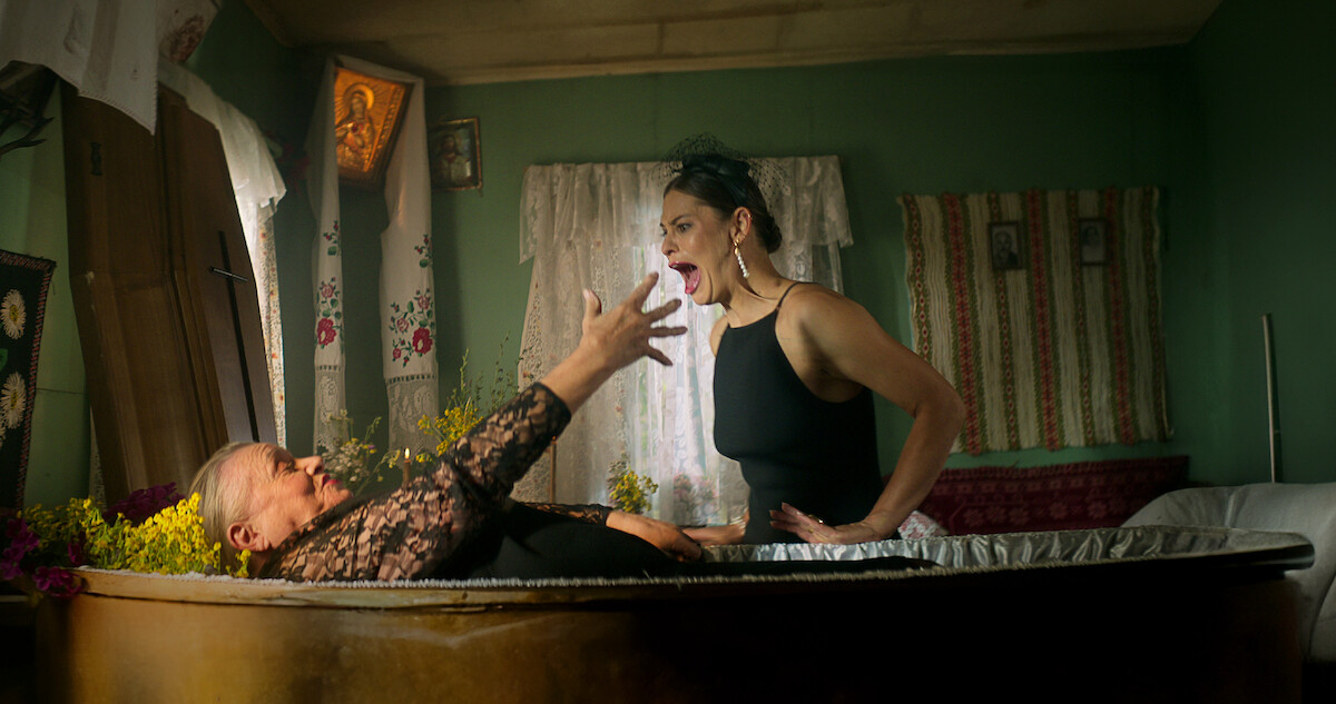 Anna Seniuk lays in a coffin stretching out her arms while Anna Szymańczyk looks on screaming in 'No Pressure'
