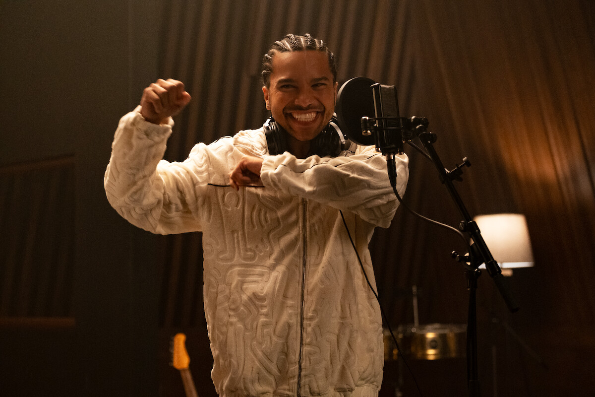 Tyler Dean Flores as Santi stands in a recording studio smiling in Season 1 of ‘Neon.’