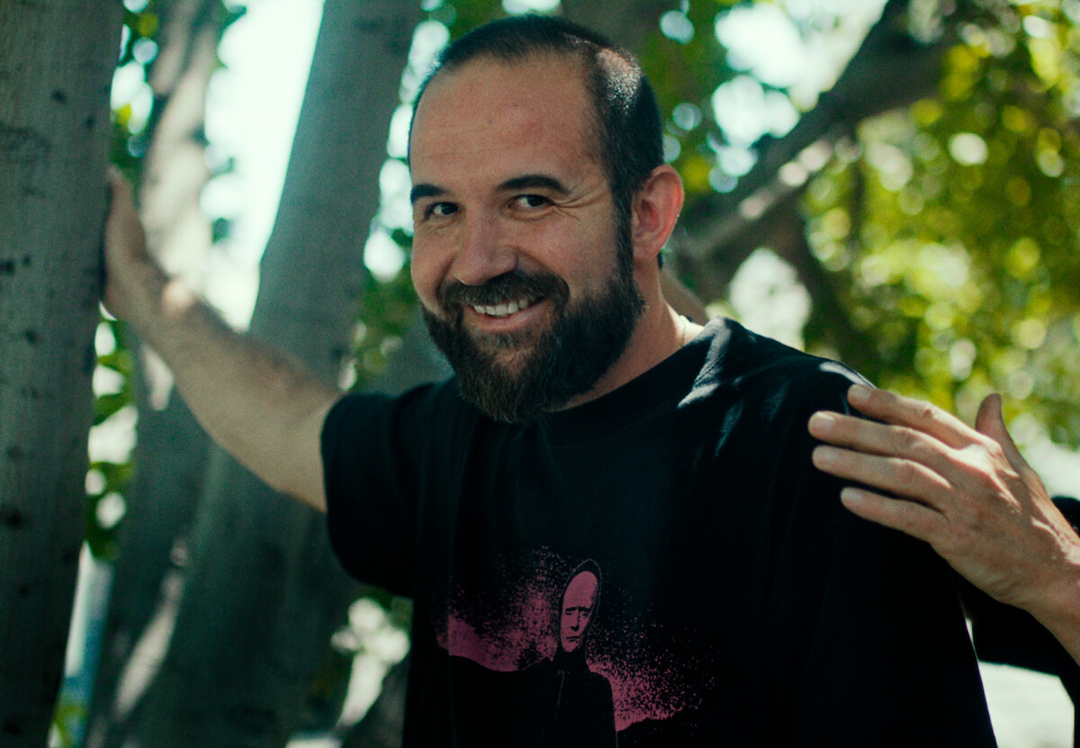 O diretor Floyd Russ é um homem branco, de barba longa e cabelos curtos. Ele aparece vestindo camisa preta e sorrindo