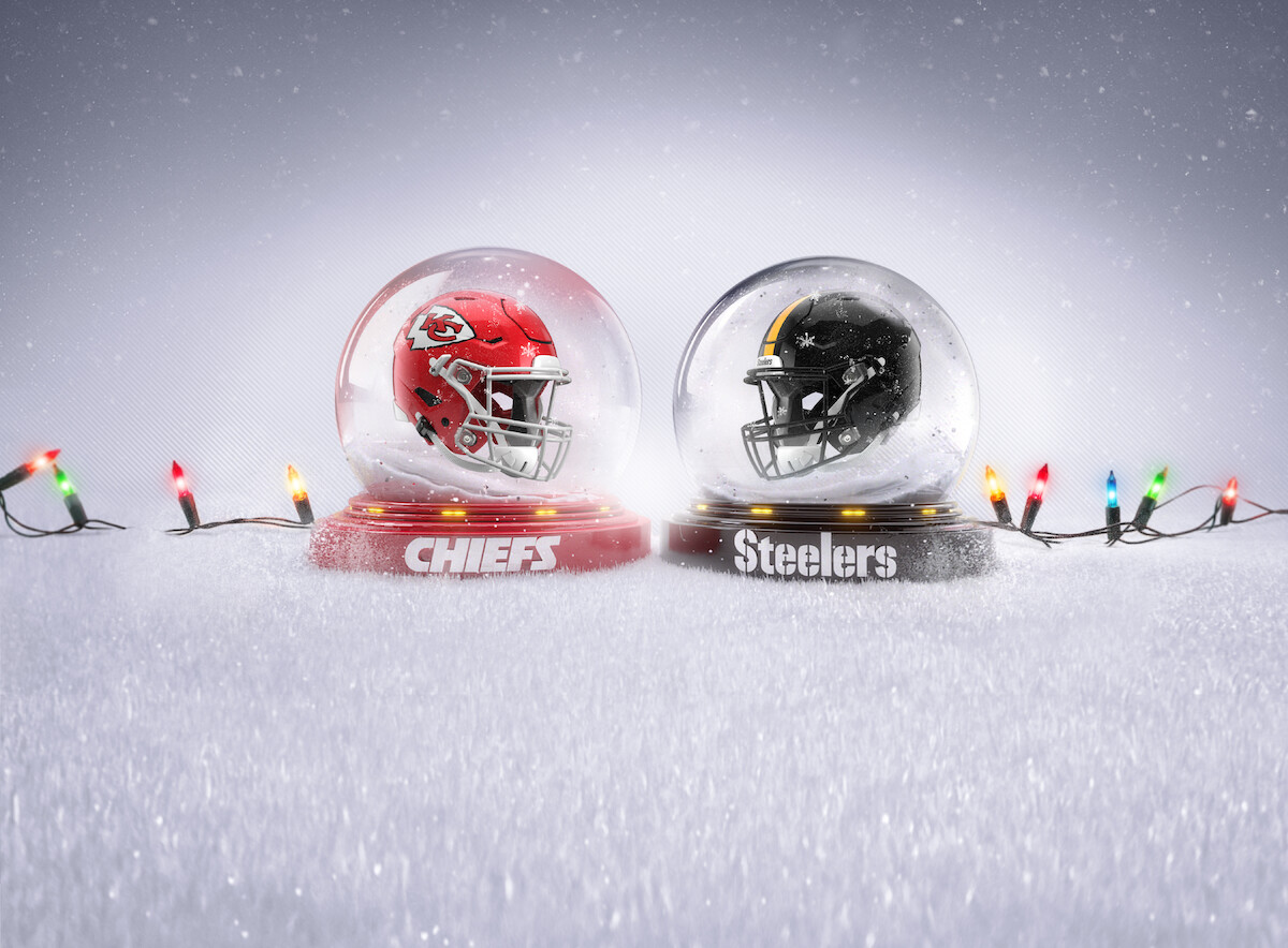 A Kansas City Chiefs and Pittsburgh Steelers helmet inside of snow globes surrounded by Christmas lights.