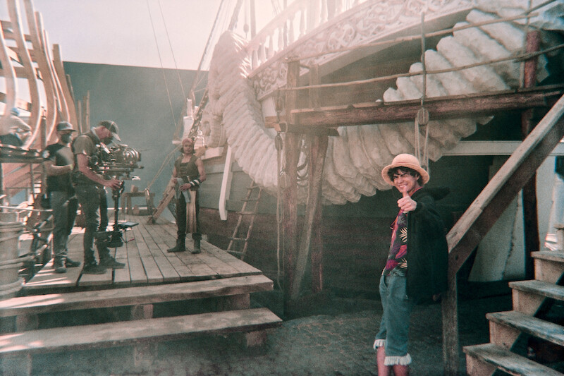 Jacob Romero as Usopp and Iñaki Godoy as Monkey D. Luffy stand in front of a pirate ship set in Season 1 of 'One Piece.'