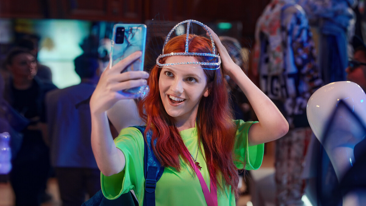 Emily Carey as Harriet Manners takes a selfie to show off her bejeweled baseball hat in an image from the series 'Geek Girl.'