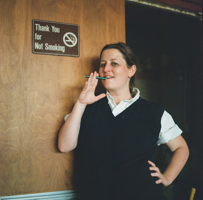 Katherine Kubler smoking in front of a sign that says "Thank you for not smoking" at Ivy Ridge. 