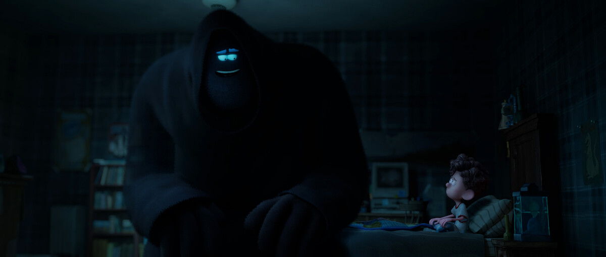 A huge hooded figure sits next to Orion on his bed in a still from ‘Orion and the Dark.’