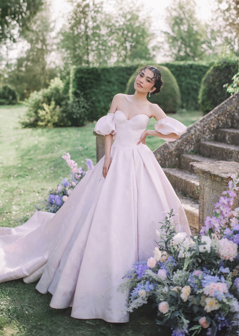 Woman in bridal dresses poses and looks off into the distance.