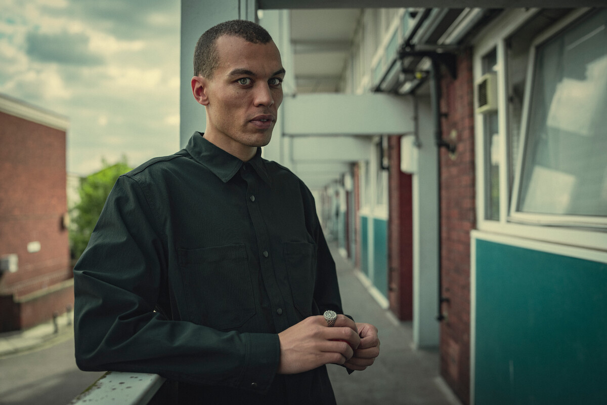 Dudley O'Shaugnessy as Si leans against a railing in Season 3 of ‘Top Boy.’