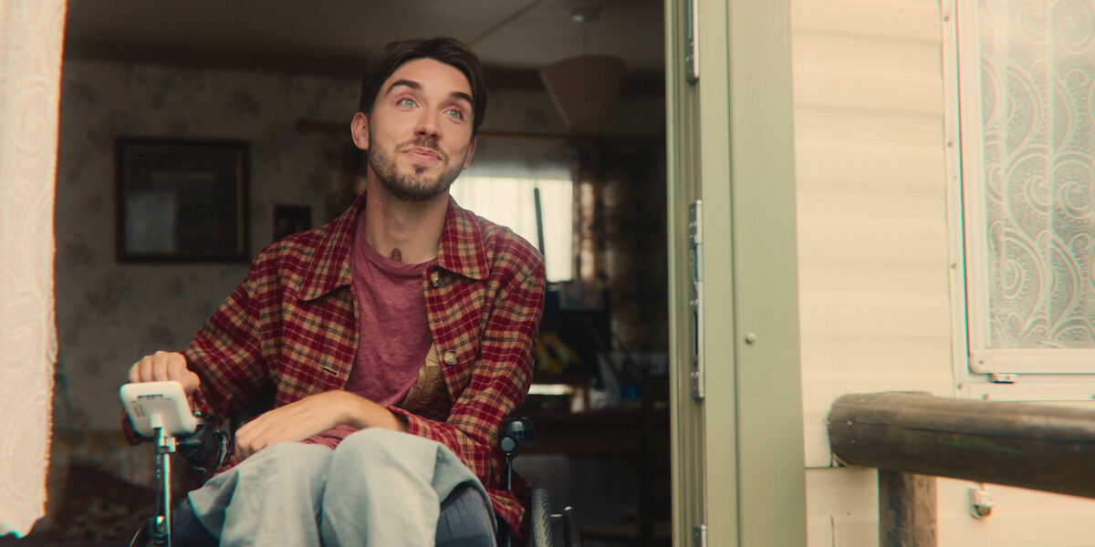 George Robinson as Isaac sits in the doorway of a trailer in Season 4 of ‘Sex Education.’