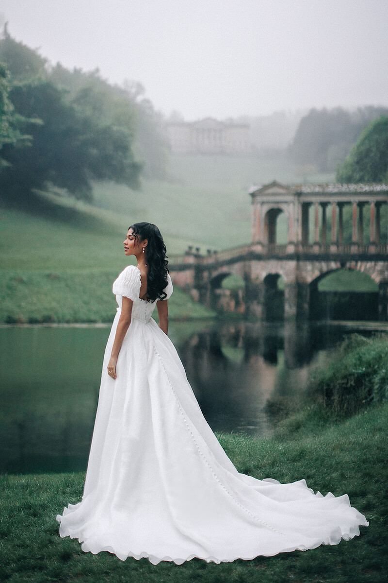Woman in bridal dresses poses and looks off into the distance.