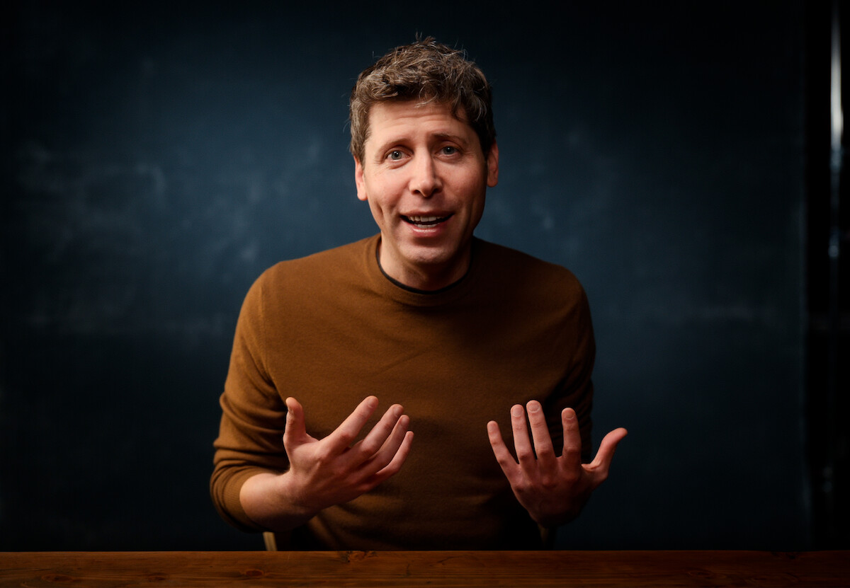 Sam Altman é um homem branco e magro, de cabelos castanhos e curtos. ele veste uma camisa de manga comprida de cor marrom, lisa