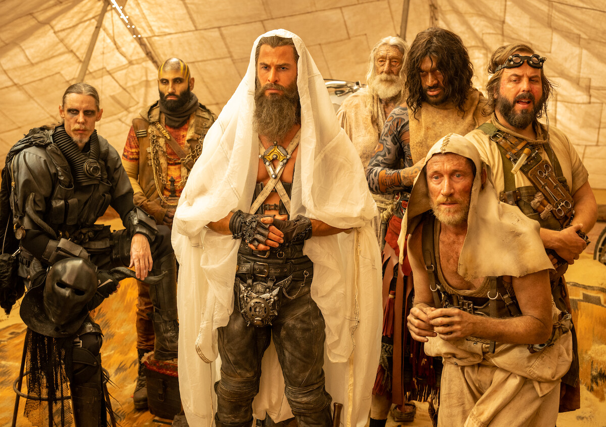 Chris Hemsworth as Dr. Dementus in ‘Furiosa’ with members of the Biker Horde next to him looking at Furiosa who is out of frame.
