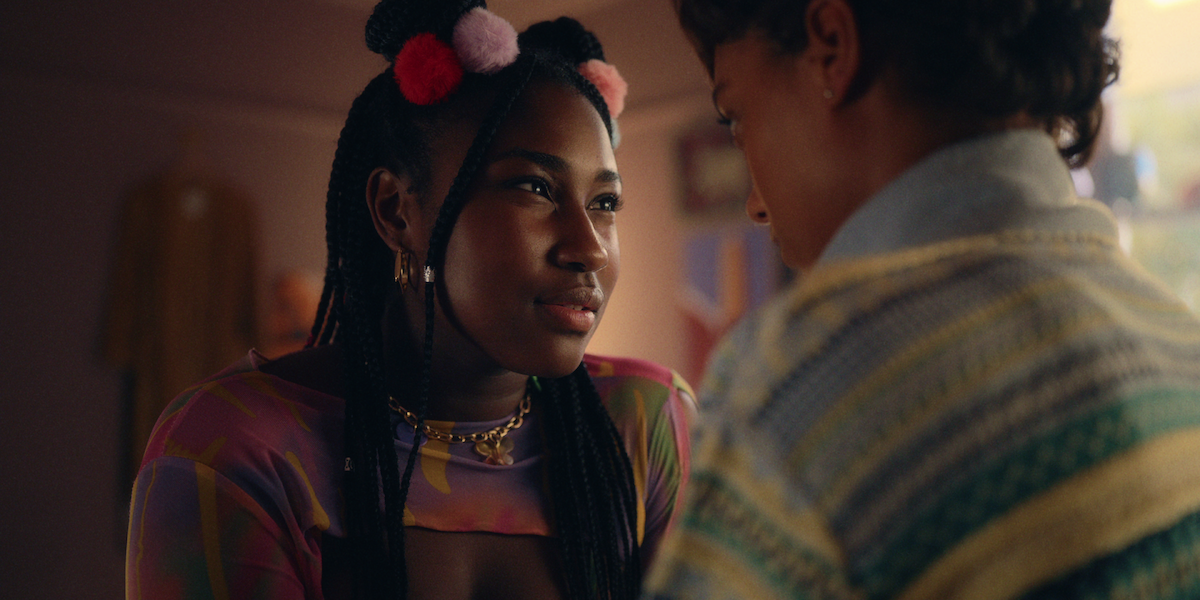 Lauryn Ajufo as Becca sits in a bedroom facing Sophie Wilde as Mia in Season 1 of ‘Everything Now.’