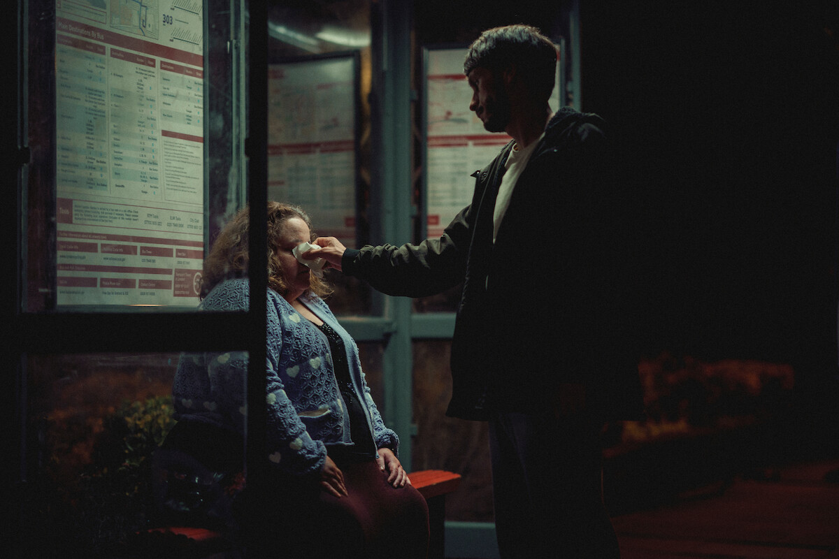 Jessica Gunning as Martha sits at a bus stop while Richard Gadd as Donny Dunn wipes her tears away in ‘Baby Reindeer.’