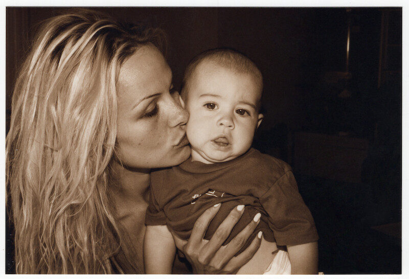 Pamela giving her infant son a kiss on the cheek.