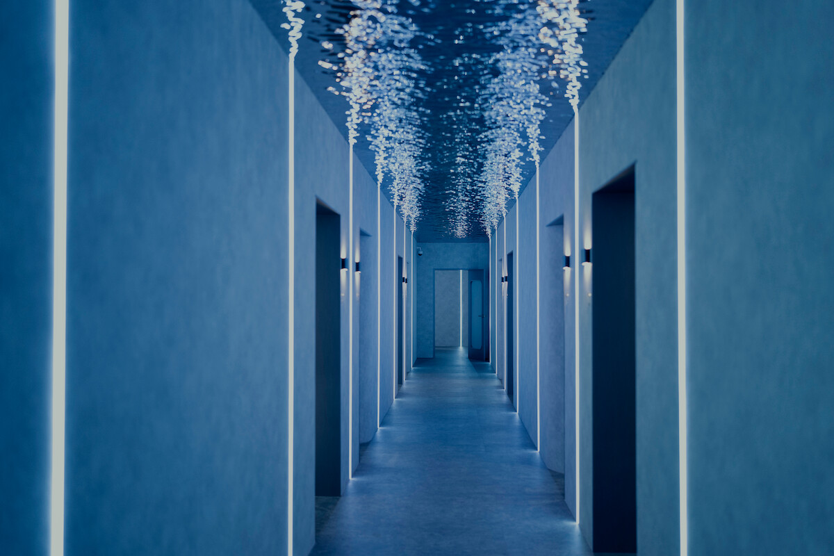 Modern hallway with minimalist blue walls, evenly spaced doorways, soft lighting, and decorative ceiling lights, creating a futuristic and serene atmosphere.