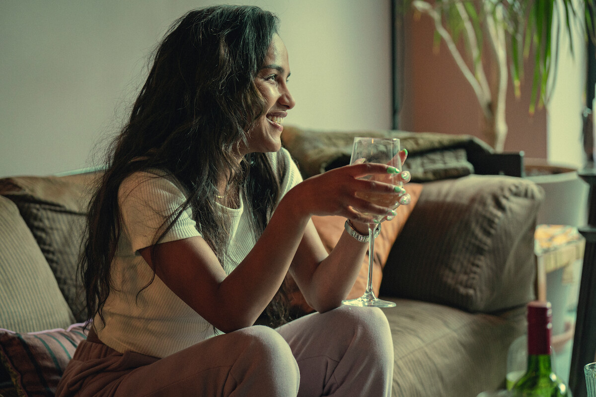 Saffron Hocking as Lauryn sits on a couch holding a glass of wine in Season 3 of ‘Top Boy.’