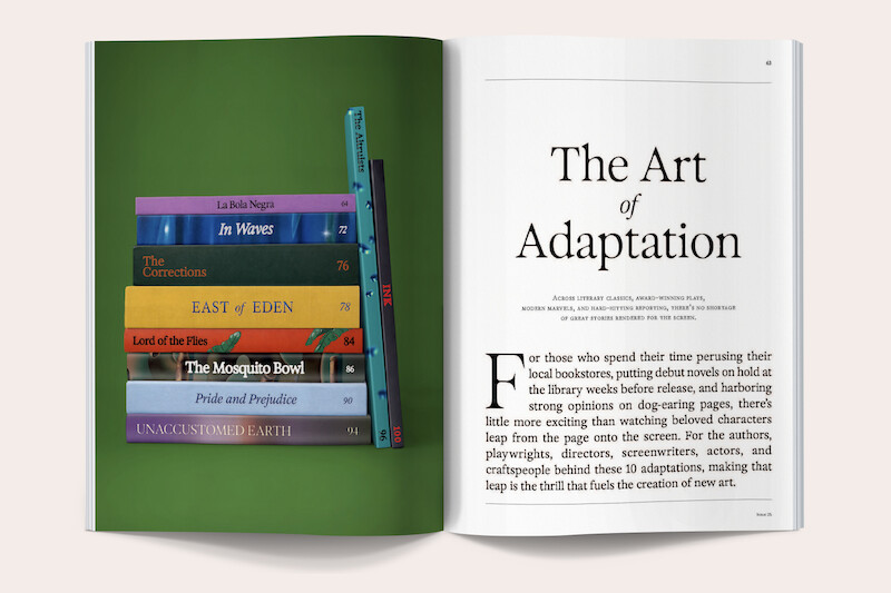 Stack of colorful books against a green background on the left page, text article titled "The Art of Adaptation" on the right page of an open magazine, suggesting a literary environment and theme about book adaptations.