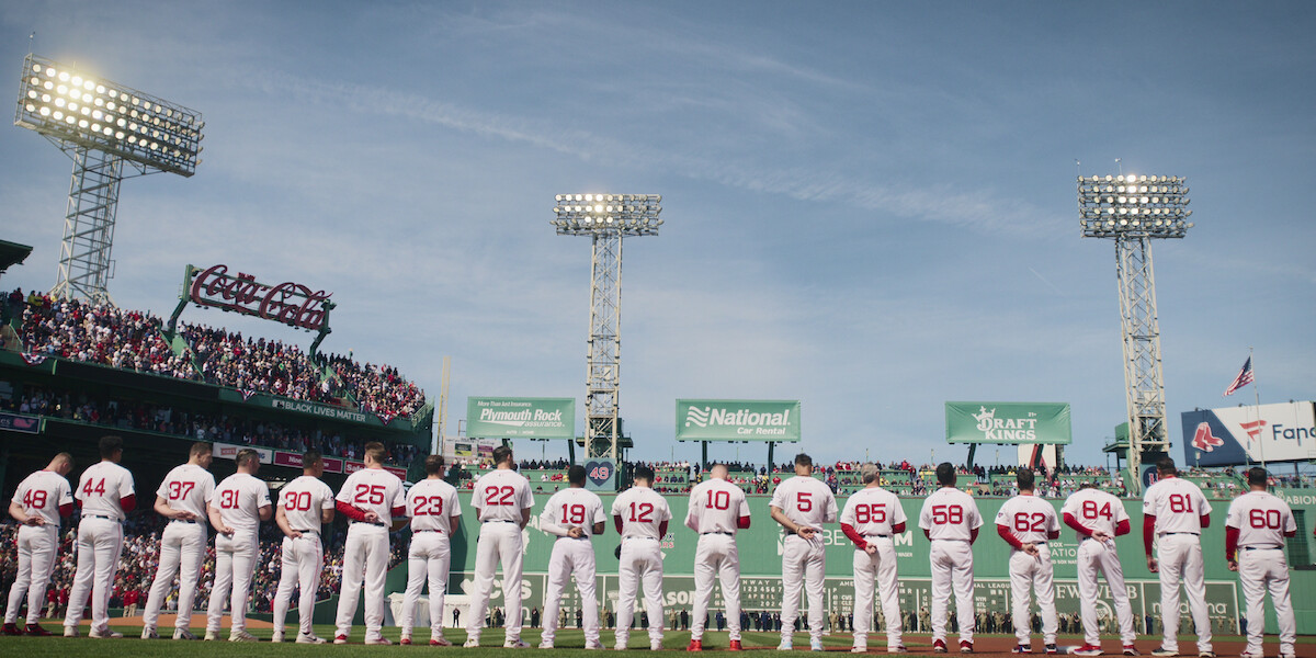 Boston Red Sox players lined up for the national anthem facing The Green Monster at Fenway Park