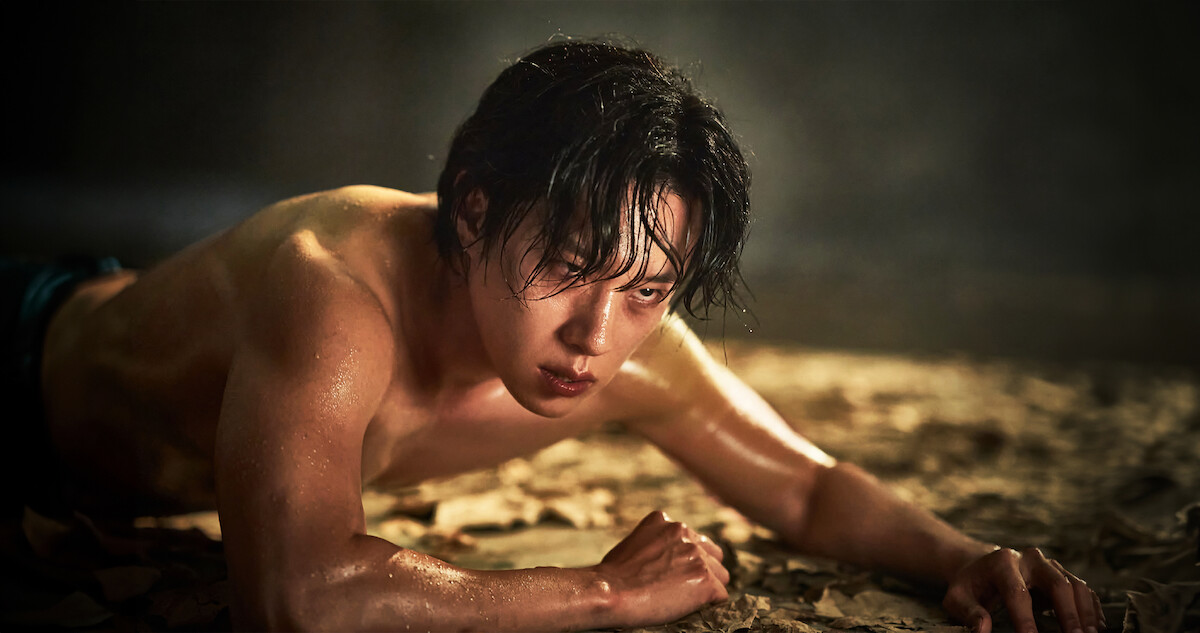 Kim Sung-Cheol as Jung Jinsu crawls on the ground shirtless in an image from 'Hellbound' Season 2.