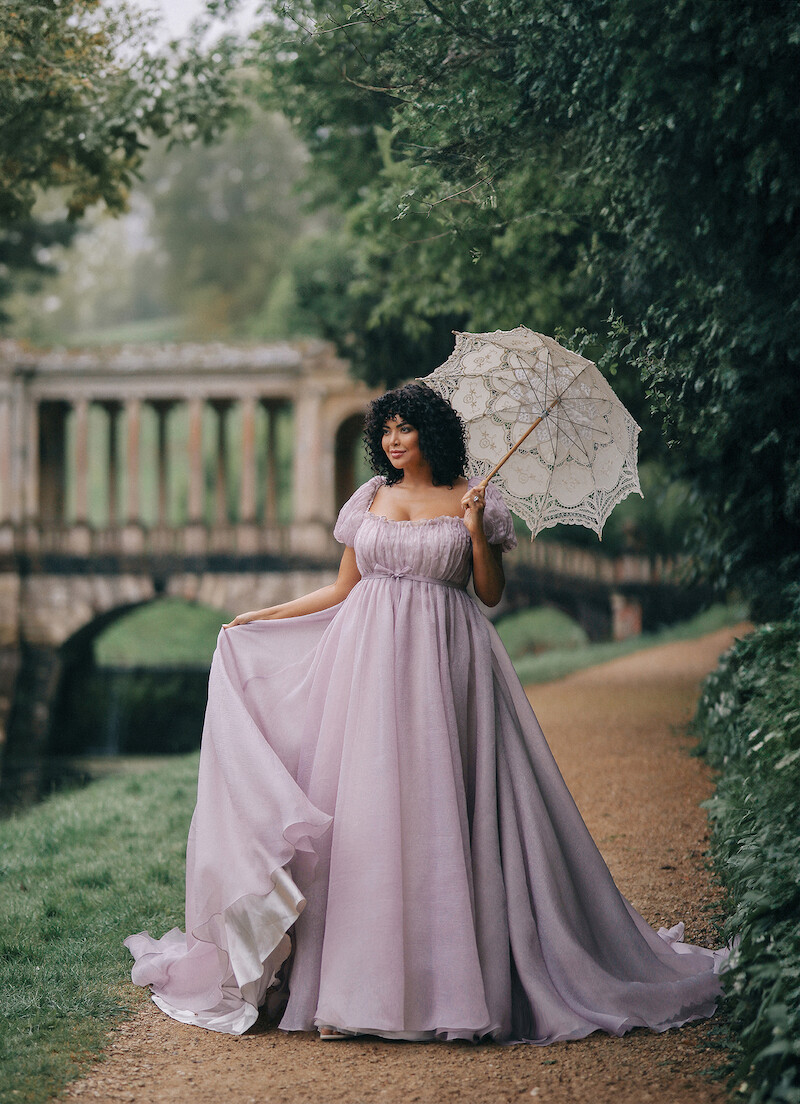 Woman in bridal dresses poses and looks off into the distance.