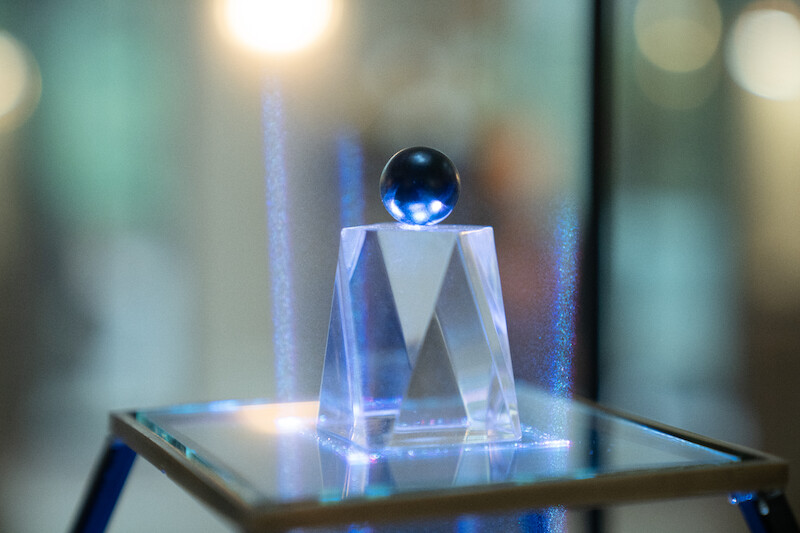 A small blue ball rests on a glass pedestal in Season 3 of 'Lupin.'