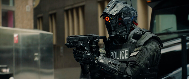A policeman full body armor stands holding a gun in 'Code 8'