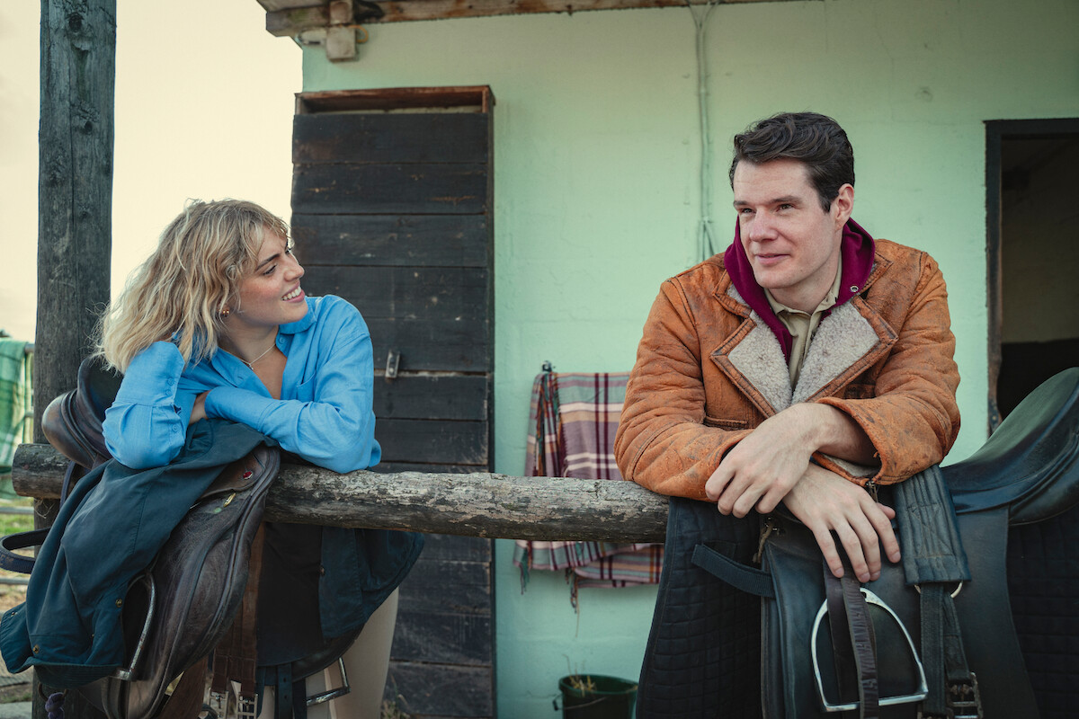 Connor Swindells as Adam leans on a railing at a horse farm in Season 4 of ‘Sex Education.’