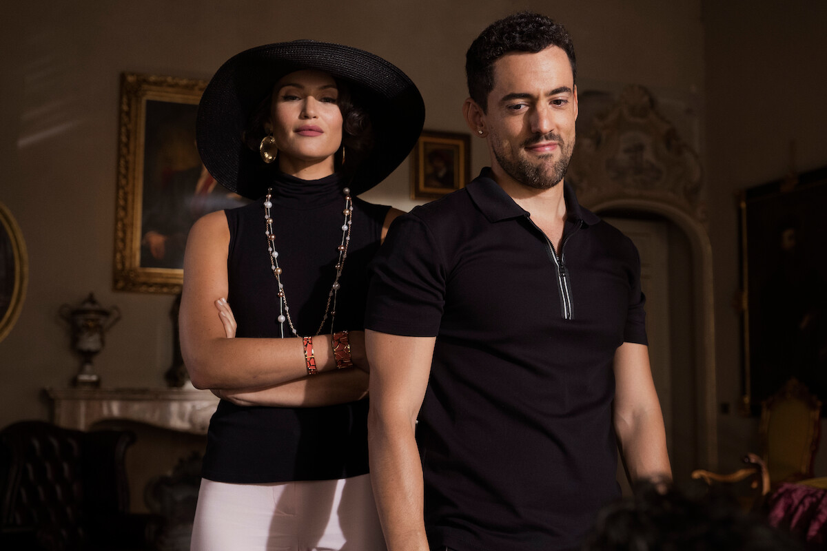Gemma Arterton wearing a black hat stands next to Luis Gerardo Méndez.