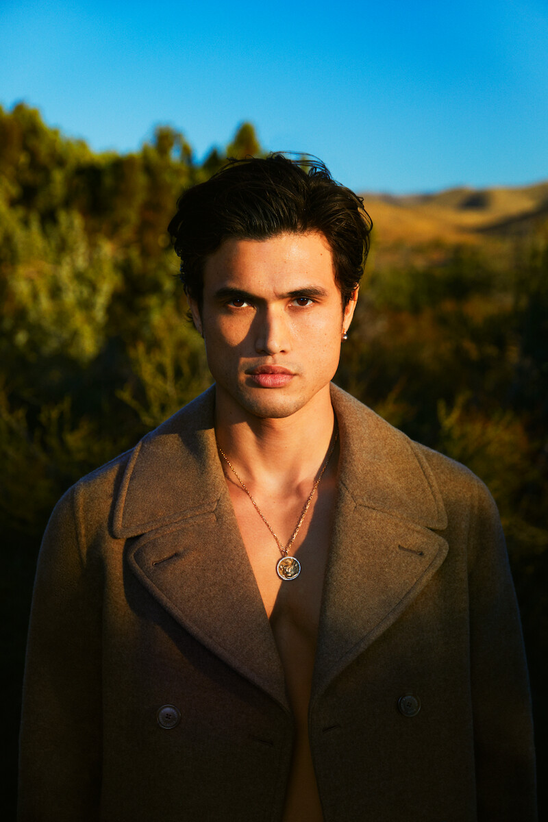 Charles Melton poses facing the camera.