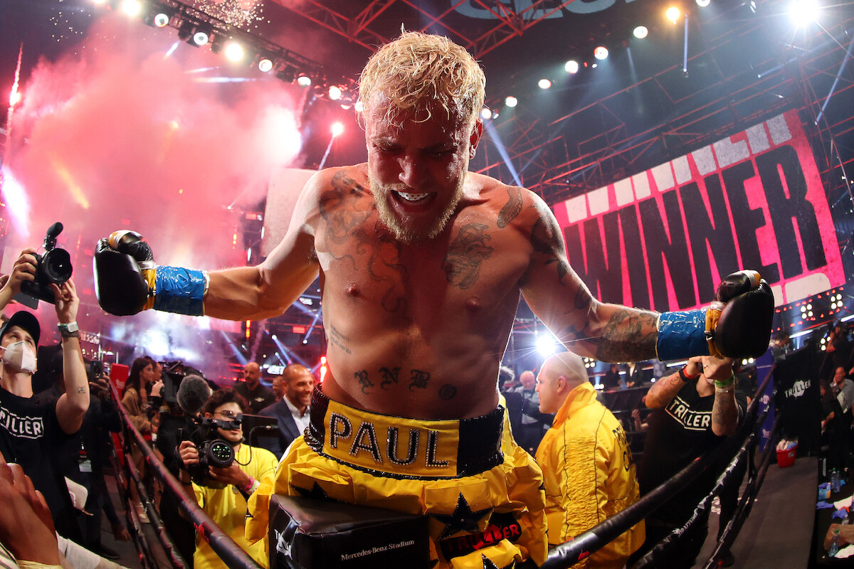 Jake Paul in trunks celebrating in front of a ‘winner’ banner